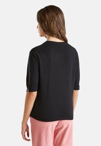 Czarny sweter z krótkim rękawem wykonany z miękkiego dzianiny, z okrągłym dekoltem i luźnym krojem. Gładka faktura i minimalny design.