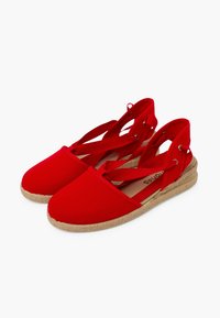 Espadrilles de lona roja con correas entrelazadas, suelas de cuerda de yute y diseño de punta redonda. Tela texturizada y suave forro interior.