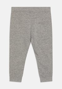 Gray cotton leggings with a soft texture, elastic waistband, and a single back pocket. Tapered fit with ankle cuffs.
