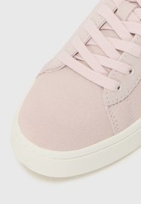 Sneaker in suede rosa chiaro con chiusura a lacci, suola in gomma bianca e dettagli cuciti sui lati. Texture liscia, design con punta arrotondata.