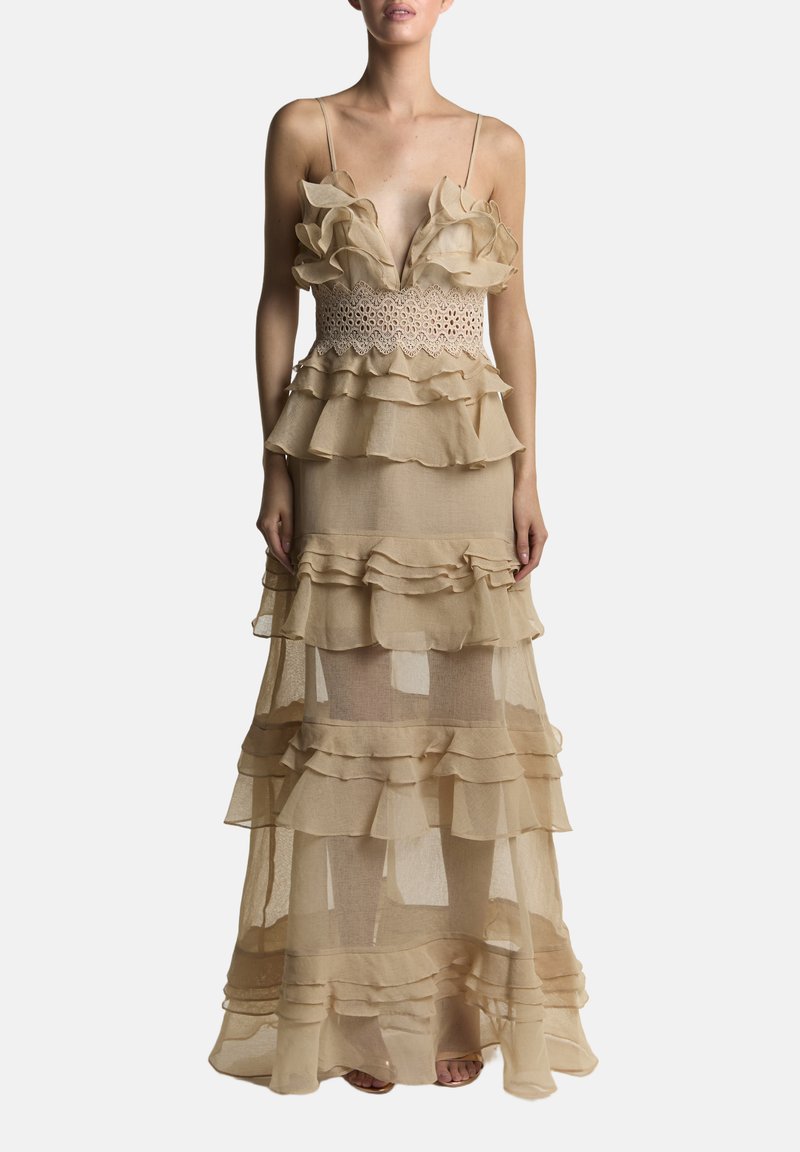 Beige flydende maxikjole med lagdelte flæser, spaghettistropper og en blondeoverdel. Gennemsigtigt stof tilføjer tekstur og visuel interesse.