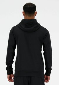 Sudadera negra hecha de una tela suave y flexible, con un corte holgado. Cuenta con capucha, mangas largas y puños acanalados. Diseño minimalista.