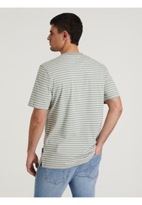 Camiseta de manga corta a rayas verdes y blancas. Tejido suave con un ajuste relajado. Presenta un cuello redondo y una pequeña etiqueta con logo en el dobladillo.