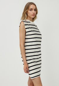 Gestreepte mouwloze jurk in crème met zwarte strepen, met een hoge halslijn en een losse silouet. Glad materiaal met minimale naden.