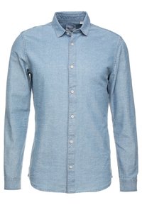 Camisa de mezclilla azul claro de manga larga con cuello abotonado, que presenta una tapeta frontal con cinco botones y un dobladillo ligeramente curvado.