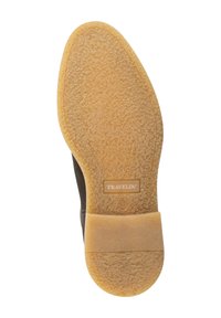 Zool van een bruine schoen met een gestructureerde lichtbruine rubberen onderkant en "TRAVELIN'" in reliëf nabij het midden.