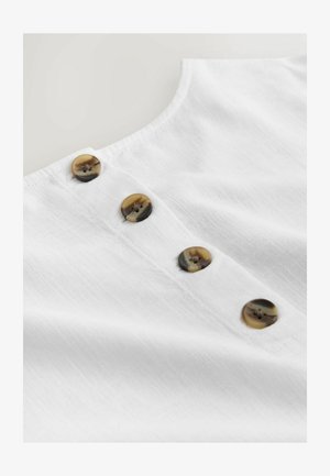 Valkoinen pellavapaita, jossa kaareva pääntie ja kolme ruskeaa kuvioitua nappia nappilistalla. Pehmeä tekstuuri, kevyt ja hengittävä tuntuma.