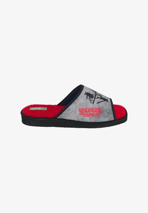 Zapatilla sin cordones gris y negra con interior rojo, con el logo de "Stranger Things" y siluetas de un niño en bicicleta y una niña extendiendo la mano.