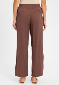 Bruine, wijde broek gemaakt van lichtgewicht stof, met een elastische tailleband en twee achterzakken, met een gladde textuur.