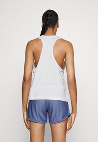 Canotta bianca senza maniche con design racerback, abbinata a pantaloncini blu scuro con tasche laterali. Tessuto morbido con una vestibilità comoda.