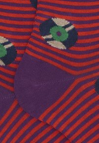 Lila und orange gestreifte Socken mit einem kreisförmigen Schallplattendesign in der Mitte grün und schwarz, Strickstruktur und gerippten Bündchen.