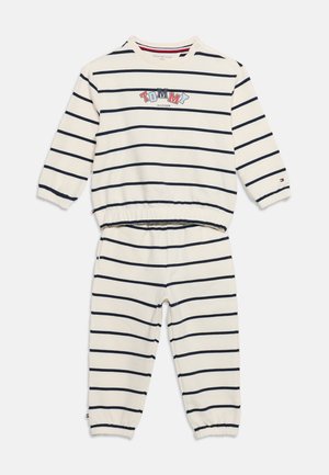Tenue blanche à manches longues pour enfants avec des rayures horizontales bleu marine, des poignets élastiques et le logo "Tommy Hilfiger" sur le devant en haut.