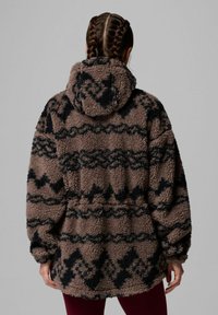 Felpa in pile marrone con motivi geometrici neri, dotata di un ampio cappuccio, maniche lunghe e una vestibilità comoda. Tessuto morbido e texture.