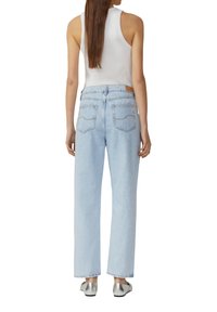 Jean taille haute bleu clair avec une coupe décontractée, cinq poches, détails de couture subtils et une étiquette en cuir au dos de la taille.