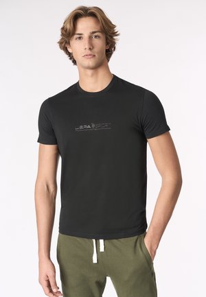 T-shirt nero aderente realizzato in morbido tessuto, con un sottile logo argentato al centro. Collo rotondo e maniche corte.