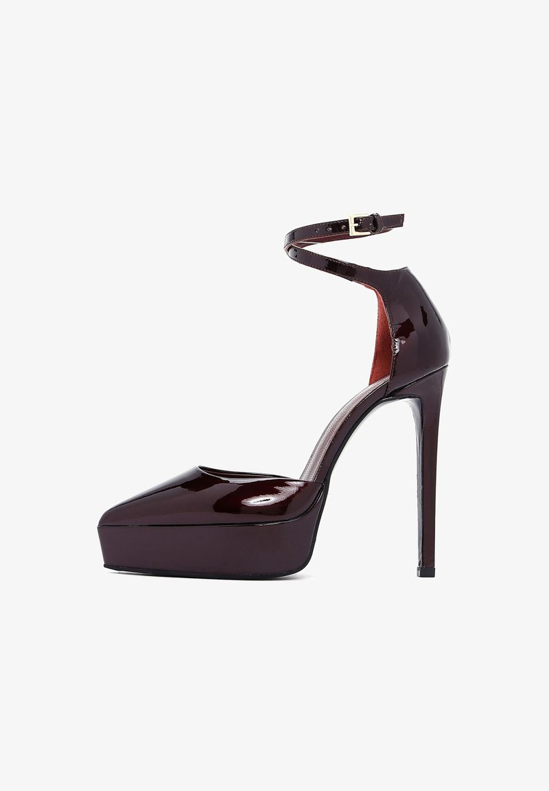 Chaussure à plateforme à talons hauts en cuir verni bordeaux foncé, avec une lanière de cheville et un design à bout pointu. Elle présente un talon aiguille et une texture lisse.