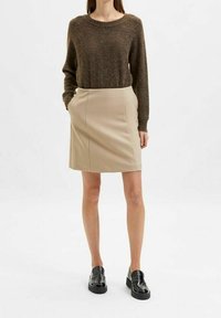 Brun ulltröja, beige figursydd kjol, svarta snörskor. Enkelt mönster, strukturerad tyg, knälång kjol med sidfickor.