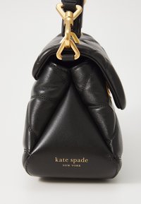 Crna kožna torba s mekim, quilted dizajnom. Ima zlatne metalne detalje i otisnuti logo "kate spade NEW YORK" sprijeda.
