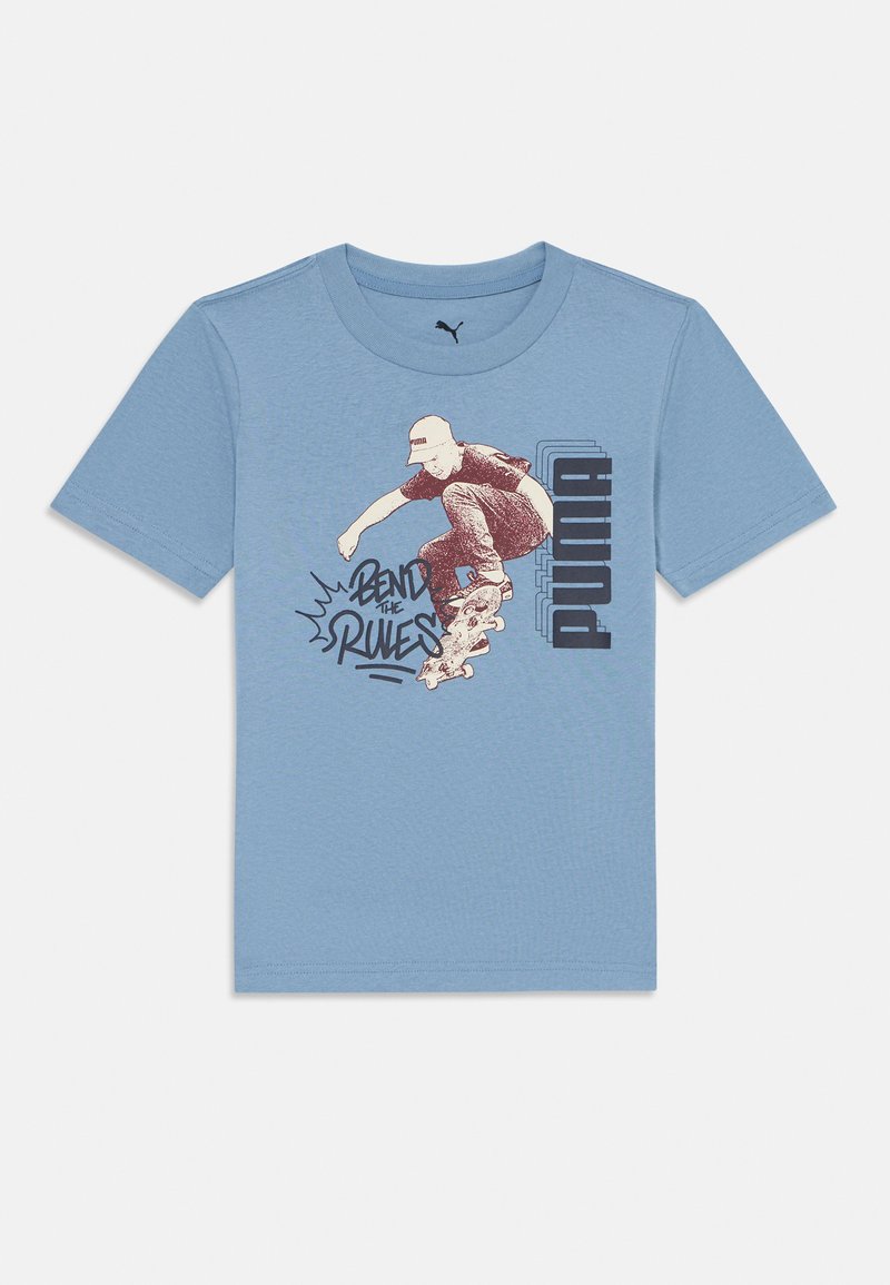 Lys blå Puma T-skjorte med en skateboarder i luften og teksten "Bend the Rules" ved siden av en stablet Puma-logo.