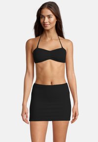 Zwarte bikini top met een gestructureerd ontwerp, voorzien van dunne bandjes. Gecombineerd met een bijpassende zwarte hoge taille rok.