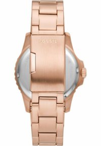 Roségoldener Metall-Uhrenarmband mit gebürsteter Textur und polierten Akzenten. Ausgestattet mit einem Verschluss mit dem "FOSSIL"-Logo. Rundes Gehäuse ist sichtbar.
