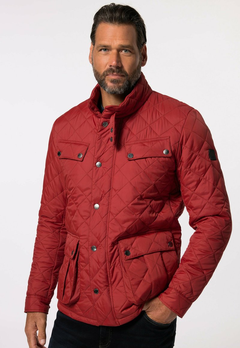 Rote gesteppte Jacke mit hohem Kragen, vorderer Druckknopfverschluss, zwei Fronttaschen und einem strukturierten Stoff. Mit schwarzen Metallakzenten.