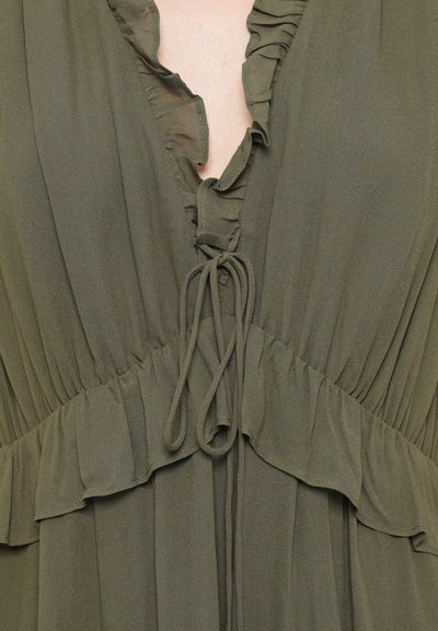 Olívová zelená šaty s volánovým výstrihom a tiered látkou. Obsahuje šnúrku v páse a vzdušnú textúru.