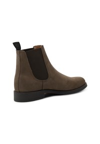 Brown suede Chelsea boot with elastic side panels, round toe, and textured pull tab; features a flat black rubber sole and stitching details.