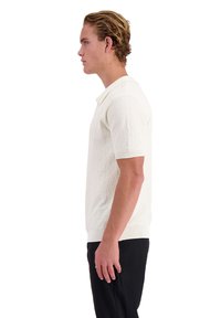Korte mouwen polo shirt van gestructureerde crèmekleurige stof met een contrasterende gele kraag. Getailleerde stijl en geribde manchetten, gedragen met zwarte broek.