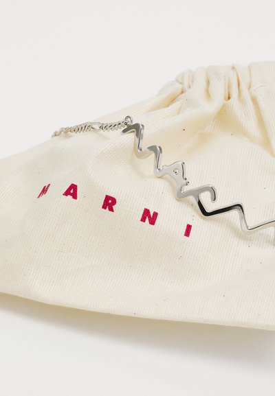 Oficiali drobės maišelis off-white spalvos su raudonu "MARNI" tekstu. Yra sidabrinis, zigzago formos metalinis akcentas. Paprastas ir funkcionalus dizainas.