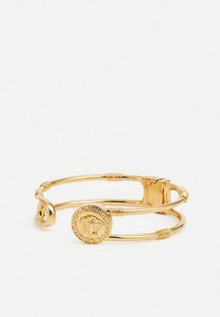 Gouden dubbellaags armband met Griekse sleutelpatroon schijf met een Medusa-hoofd en gladde, gebogen accenten op een open armband.