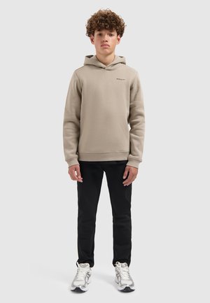 Beige sweatshirt met capuchon, geribbelde manchetten en klein logo op de borst, gecombineerd met zwarte broek en zilveren sneakers. Glad textuur van de stof.