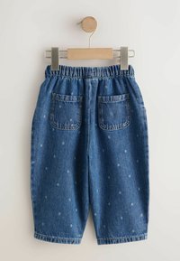 Pantalones cortos de mezclilla con cintura elástica, lavado azul claro y patrón de lunares dispersos. Cuenta con dos bolsillos traseros. Cuelga de una pinza de madera.