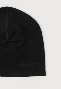 Čierna čiapka typu beanie z mäkkej, textúrovanej látky s jemným vzorom. Má nízky profil a nenápadné logo "Houdini" na boku.
