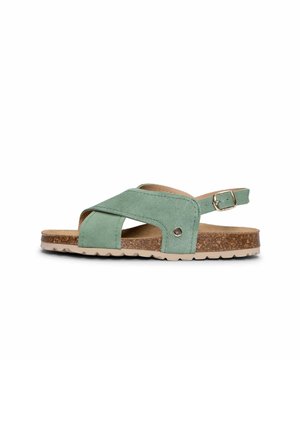 Sandalia verde de ante con puntera abierta y tiras cruzadas, plantilla de corcho, suela de goma beige y tira trasera ajustable con hebilla.