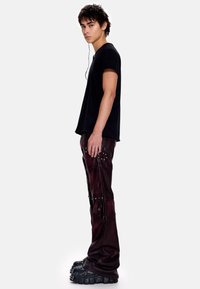 Μαύρο κοντομάνικο μπλουζάκι συνδυασμένο με σκούρο μπουρντό δερμάτινο παντελόνι με τρουκς και φερμουάρ, φορεμένο με χοντρά μαύρα πλατφόρμα παπούτσια.