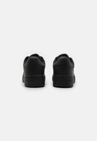 Sneakers neri in pelle con una superficie liscia. Presentano un design a taglio basso, colletto imbottito e logo impresso sul tallone.