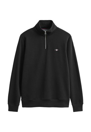 Juodas džemperis su aukštu apykakliu, pusiau užtrauktuku ir siuvinėta logotipu ant krūtinės. Minkšta tekstūra, petnešomis surišti rankogaliai ir apačia.