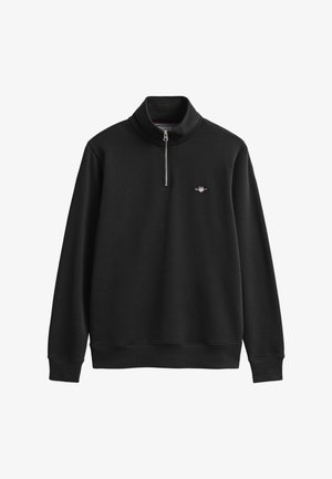 Juodas džemperis su aukštu apykakliu, pusiau užtrauktuku ir siuvinėta logotipu ant krūtinės. Minkšta tekstūra, petnešomis surišti rankogaliai ir apačia.