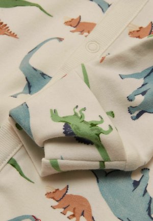 Weicher Cremestoff mit bunten Dinosaurier-Prints in Grün, Blau und Braun, darunter langhalsige und gehörnte Arten, auf gefalteter Kleidung.