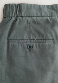 Grå stofshorts med elastisk talje, med kontraststing, en baglomme og en mørk knaplukning.