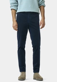 Marineblauwe corduroy broek met een slim fit, voorzien van een platte voorkant, vijf-pocket ontwerp en subtiele textuur. G gedragen met een lichtblauwe trui en bruine laarzen.