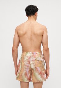 Herren-Badehorts im Batikmuster, das in sanften Tönen von Pfirsich, Grün und Creme gehalten ist, mit elastischem Bund und einer Gesäßtasche.
