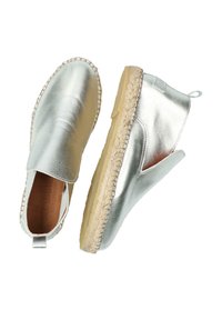 Scarpe slip-on in pelle argento con punta rotonda, suola in juta e dettagli cuciti. Presentano un profilo basso e un tassello sul retro per indossarle facilmente.