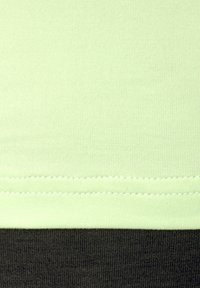 Minzgrüner Baumwollstoff mit einer gerippten Textur oben, der zu einem dunkleren grauen Stoff unten übergeht und sichtbare Nähdetails aufweist.