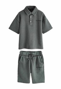 Tmavosivé textúrované tričko s krátkymi rukávmi a golierom na gombíky a zodpovedajúce elastické šortky s sťahovacou šnúrkou v páse, obe s logom značky "ALLSAINTS".