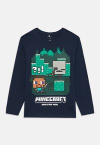 Laadukas tummansininen pitkähihaisen t-paita, jossa on pikselöityjä Minecraft-hahmoja, vihreästä lohkotaustasta ja valkoista "Minecraft Seikkailutila" -tekstiä.