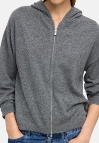Szara hoodie na zamek, wykonana z miękkiej dzianiny, z kapturem, ściągaczami przy rękawach oraz przednim zamkiem z metalowym uchwytem. Luźny krój.