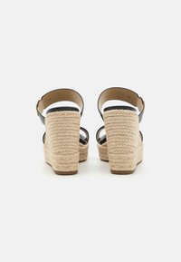 Sandale negre cu toc wedge, având o platformă texturată din jute natural, cu un design cu o singură curea, curea ajustabilă la gleznă și talpă din cauciuc.