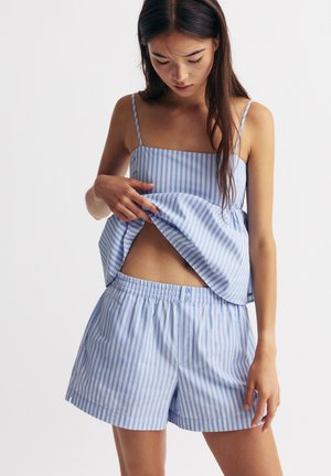 Top bleu deschis cu dungi, cu bretele subțiri și pantaloni scurți asortați, având un brâu elastic și închidere cu buton, confecționat dintr-o țesătură moale.